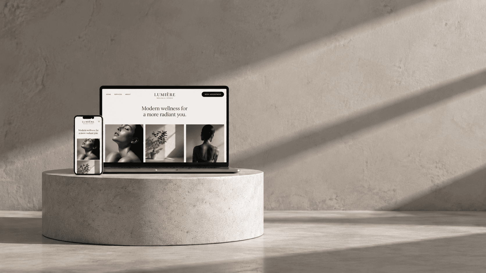 Laptop and phone showing a wellness studio website on a stone pedestal
